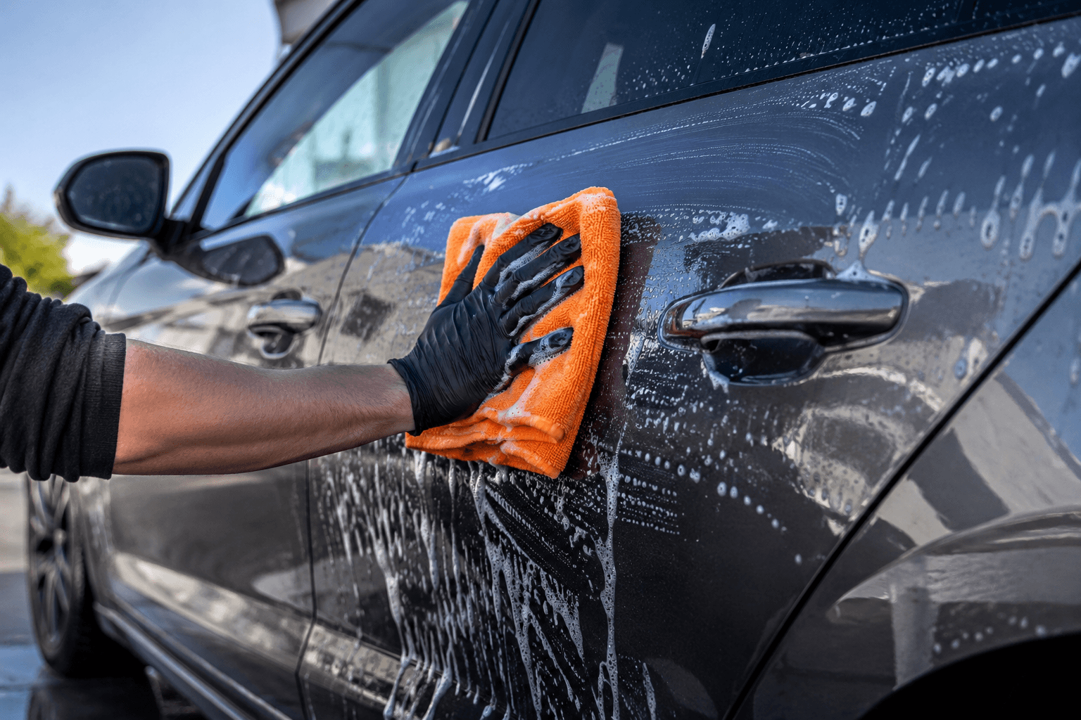 Professionele handwas van een donkere sedan — schuim op de carrosserie
